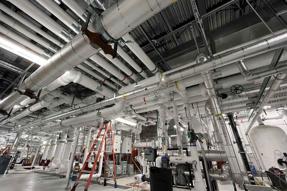 Commercial mechanical room with insulated piping and HVAC systems installed by Acorp Industries.